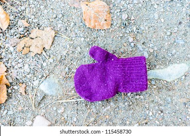 Lost And Found. A Purple Mitten Lying On The Ground Where A Child Dropped Or Misplaced It.