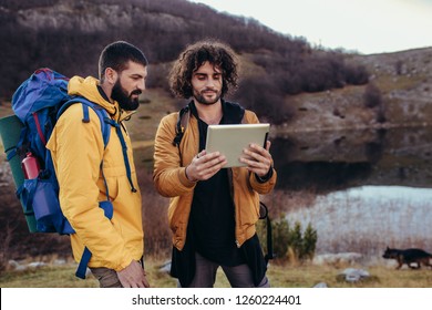 Lost Hiker Looking At The Way Through Map On Digital Tablet During Hiking In Wilderness