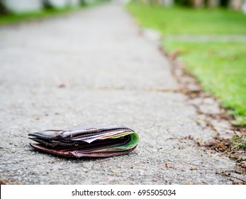 Lost leather wallet with money drop on sidewalk , lost money concept, copy space on top.