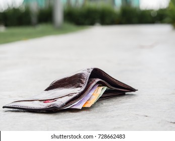 Lost leather wallet with money drop on sidewalk , lost money concept, copy space on top.