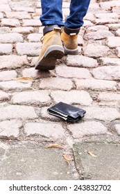 Lost leather wallet and walking male legs, outdoors