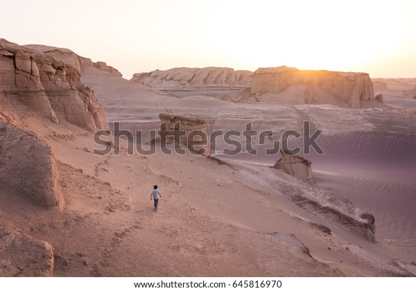 日の出と共にピンクの砂漠の砂の中をさまよう迷子の男が イラン南部のバロキスタンのルト砂漠で 太陽が砂岩の形を崩すのを見て の写真素材 今すぐ編集