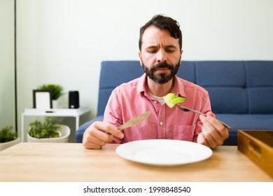 I Lost My Appetite. Attractive Man Trying To Eat A Green Salad Alone At His Home. Sad Man With An Eating Disorder