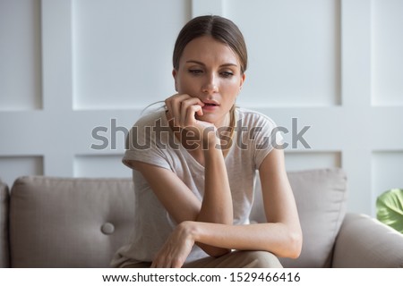 Lost on sad thoughts millennial 30s woman sitting on couch at home feels emptiness by personal difficulties and unsolvable problems, concept of jealous wife, lonely single frustrated female concept
