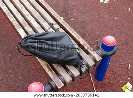 A lost school backpack lying on a park bench. A lonely bag in the park.