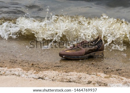 A Lost Shoe on the Beach almost Covered by the Waves