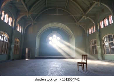 lost spaces, big abandoned dancing hall with big white windows, green walls, dust on the floor, sun light and an empty chair                               