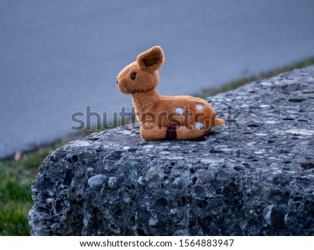 Lost stuffed animal that looks like a bamby toy sitting on a stone