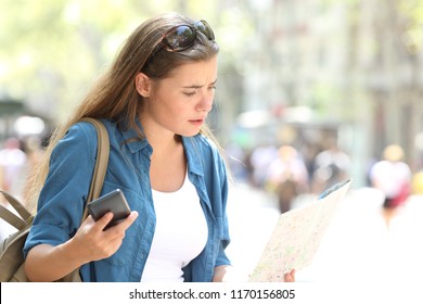 Lost tourist searching direction in a map and a phone in the street - Shutterstock ID 1170156805