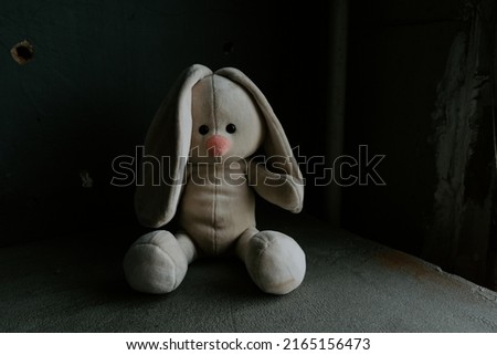 Lost toy bunny is sitting alone in a room. War, death and lost childhood theme.