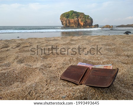 Lost wallet at the beach. brown leather wallet filled with money dropped on the sand