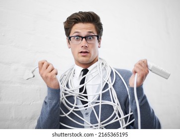 Lost In Wires. A Young Nerdy Guy Tangled Up In Cables.