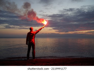 Losted Man On A Beach Holding Emergency Fire, Rescue Concept.