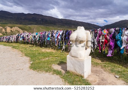 lots of bra hangs on the fence with a Stone statue in New Zealand.