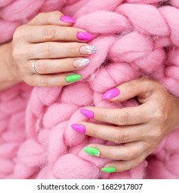 Lots color gloss manicure hands has different blotches in pink background  Hands wrapped in blanket Merino yarn  On the nail there is picture papaya fruit