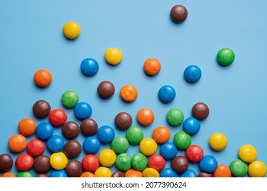 Lots Of Colorful Smarties Sweets On Blue Isolated Background. Color Close Up Studio Photo.