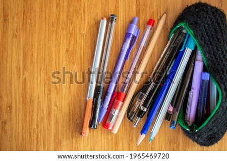 Lots of different pen and pencils spreading through black pencil holder on wooden table.Study for exams and education concept. Pile of pencils of different colors.copy space.work in distance education