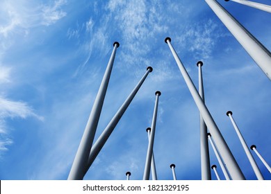 lots of empty flagpoles against a blue sky