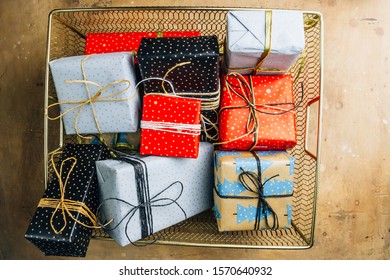 Lots Of Gift Boxes In Golden Basket. Stylish Zero Waste Presents In Black, Light Blue And Red Craft Paper Decorated With Paper Ribbon Bows. Christmas And Winter Holidays Concept. TFlat Lay