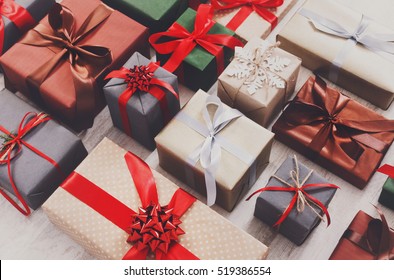 Lots of Gift boxes on wood background. Presents in craft and colored paper decorated with red ribbon bows and snowflakes. Christmas and other holidays concept.