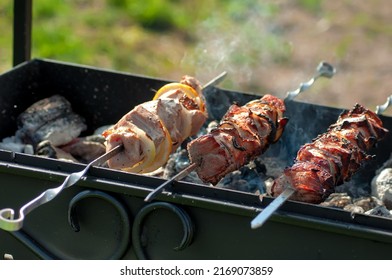 Lots of juicy meat pieces of grilled kebabs. String the pieces of meat on a metal skewer on the grill. The process of cooking kebabs with a lot of smoke. Cooking in nature
