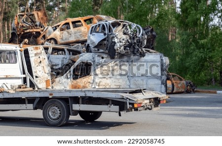 Lots of old cars ready for recycling. Car removal by tow truck. Damaged cars are waiting in a junkyard to be recycled or used for parts. The process of car recycling at a car junkyard