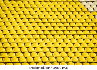 lots of rows with yellow seats for people on the football field in the summer