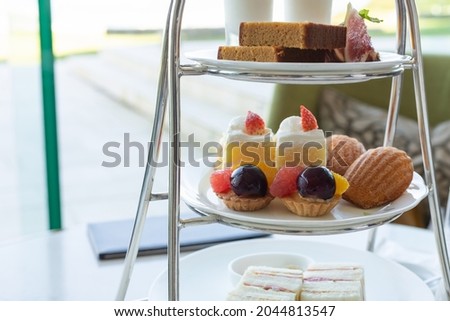 Lots of sweets piled up on a three-tiered cake stand (afternoon tea image)