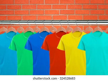 Lots of T-shirts on hangers over orange brick wall - Powered by Shutterstock