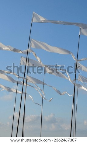 Lots of white flags on long flagstocks flapping in the wind