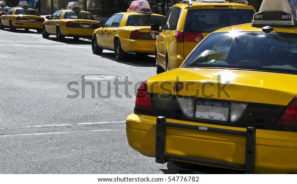 lots\
of yellow New York Taxis waiting on traffic\
lights