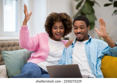 Lottery, giveaway, betting. Emotional happy beautiful african american young couple gambling on Internet at home, cheerful black lovers winners sitting on sofa, using laptop and rasising hands up - Shutterstock ID 2250275229