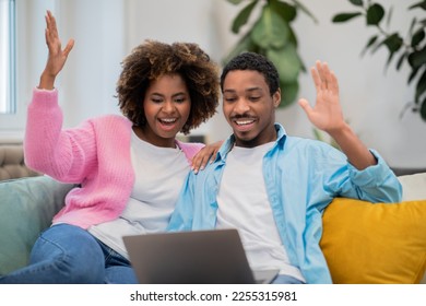 Lottery, giveaway, betting. Emotional young black couple gambling on Internet at home, cheerful black lovers winners sitting on sofa, using laptop and rasising hands up, celebrating success - Shutterstock ID 2255315981