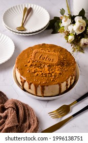 Lotus Biscoff Cheese Cake Made From Lotus Cookies And Spread, Placed On White Plate And Surrounded Another White Plates, Flower, Fork, Knife, Brown Fabric With The Marble Background