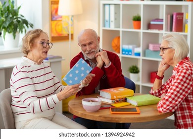 Loud Reading. Positive Mature Woman Sitting With Her Friends While Reading A Book To Them