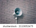 Loud speaker on brick wall. Megaphone hanging on building. City hazard warning system. Providing security in town, notification of emergencies.