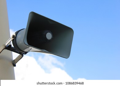 Loudspeaker Isolated On Empty Sky Background. Megaphone Speaker On Pole Against Blank Cloudy Sky. Outdoor Public Speaker Equipment And Broadcast System To Announce Important Information To Public.