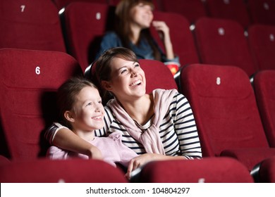 Loughing mother and daughter at the cinema watching a movie