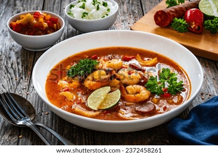 Louisiana soup gumbo with shrimp, chorizo and white rice on wooden table 