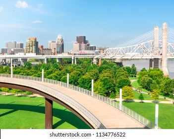 LOUISVILLE, KENTUCKY -  JULY 3, 2018:  Downtown Louisville Skyline Cityscape With Lewis And Clark Bridge, River Front Park Land And Shared Walking Bike Path