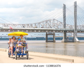 LOUISVILLE, KENTUCKY - JULY 3, 2018:  Tourist Family Riding Surrey Bike To Tour Downtown Urban Waterfront Path In Louisville, Kentucky