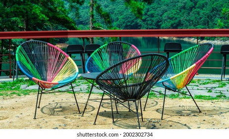 A lounge chair in an empty space facing the blue lake in the forest