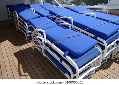 Lounge Chairs With Blue Cushions Stacked Up On Cruise Ship Wooden Deck