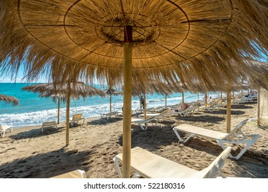Lounge chairs and straw umbrellas at the beach in Malaga. Costa del Sol, Andalusia, Spain