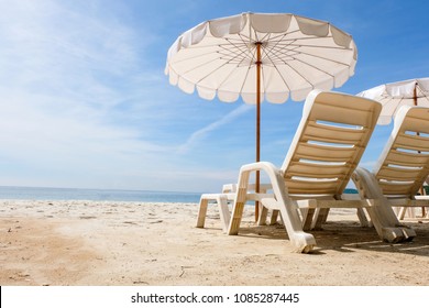 Lounge chairs with sun umbrella on a beach. Sun of summer time on sky and sand of beach relaxation landscape viewpoint. Ocean nature tranquility, Thailand.