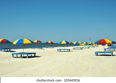 Lounge chairs, umbrellas, and oversized trikes scattered along Biloxi Beach in Mississippi on a spring day.