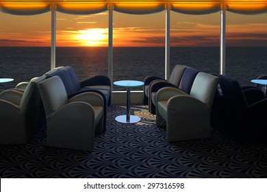 Lounge on a cruise ship, with tables and armchair in the sunset at sea 