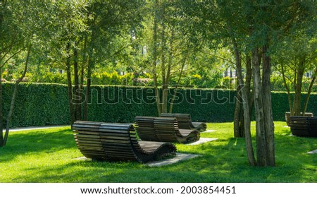 Сomfortable loungers for rest in shade of deciduous trees. Public landscape city park Krasnodar or 'Galitsky park' for relaxation and walking.  Best place for recreation and health in Krasnodar