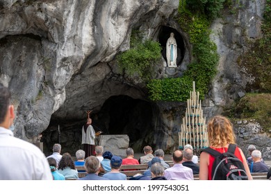 LOURDES, FRANCE - JUNE 19, 2021:group of Christian people attend mass in the grotto of the apparition of Our Lady of Lourdes, in france
