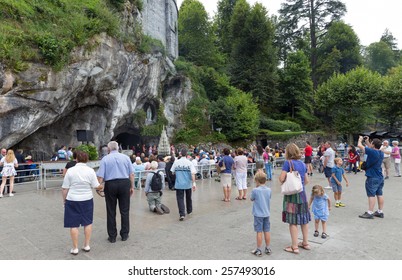 LOURDES - JULY 23, 2014: Tourists and Pilgrims visiting the cave at Massabielle in Lourdes, where St. Bernadette Soubirous claimed to have seen the Blessed Virgin Mary. It now is a religious grotto.